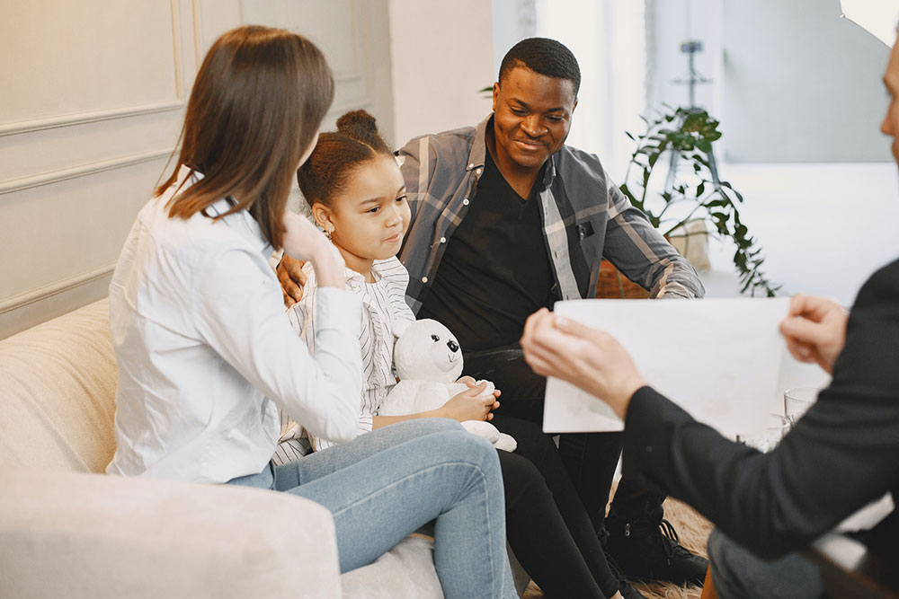 family sitting on a white couch talking to a counselor